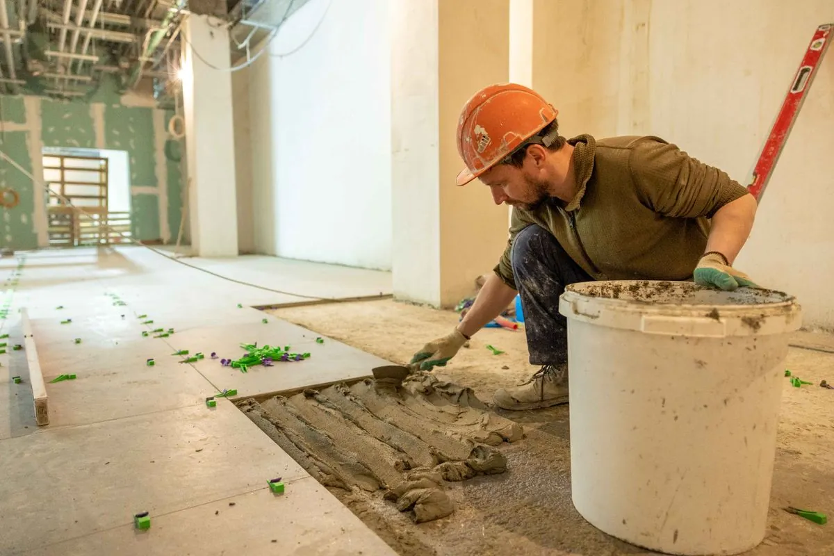 Tiler installing floor tiles with leveling spacers